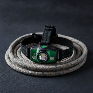 Black and green headlamp on a coiled rope
